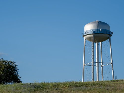 Watertower in a field against a blue sky.